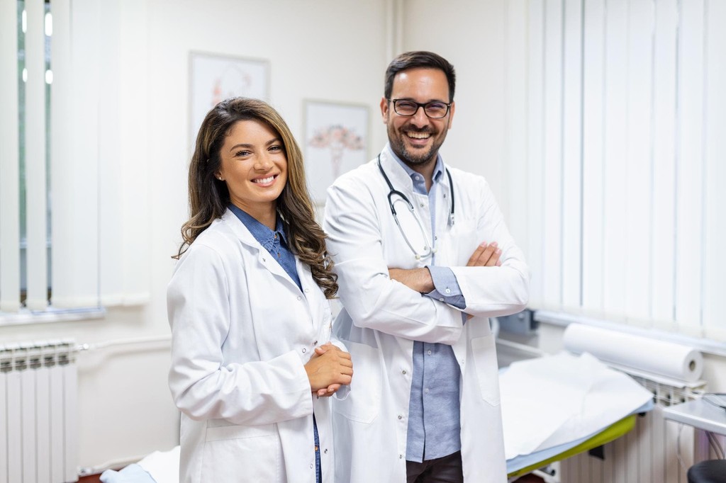 Dois médicos sorrindo em um consultório iluminado